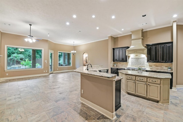 13622 Kluge Corner Ln, Cypress, TX 77429 - kitchen with a kitchen island with sink, ornamental molding, ceiling fan, open floor plan, and custom exhaust hood