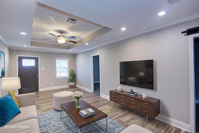 4220 Delhi St, Houston, TX 77022 - living room featuring light wood-style flooring, a ceiling fan, a raised ceiling, ornamental molding, and recessed lighting