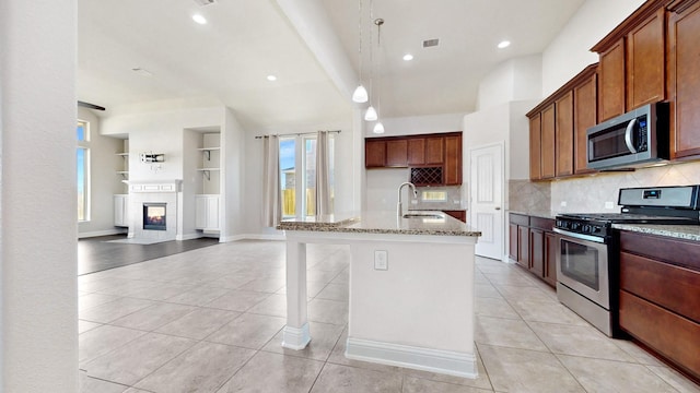 2135 Llerena Ln, League City, TX 77573 - kitchen featuring appliances with stainless steel finishes, light stone counters, light tile patterned floors, tasteful backsplash, and built in features