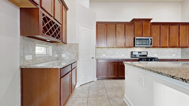 2135 Llerena Ln, League City, TX 77573 - kitchen featuring stainless steel microwave, range, light stone countertops, backsplash, and light tile patterned flooring