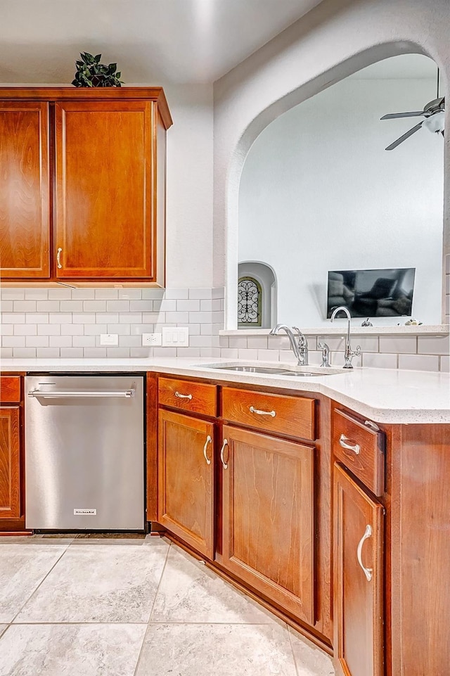 24030 Cannon Anello Ct, Katy, TX 77493 - kitchen featuring stainless steel dishwasher, arched walkways, a ceiling fan, brown cabinetry, and tasteful backsplash