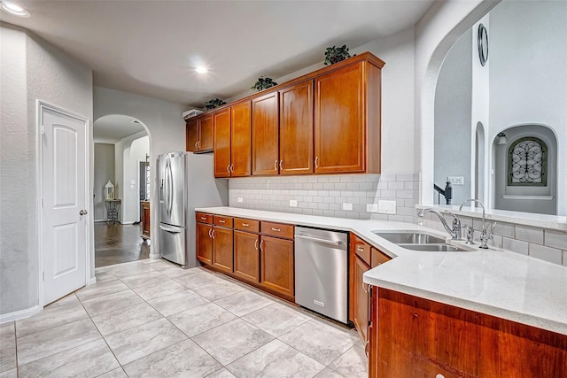 24030 Cannon Anello Ct, Katy, TX 77493 - kitchen with appliances with stainless steel finishes, arched walkways, backsplash, brown cabinetry, and recessed lighting