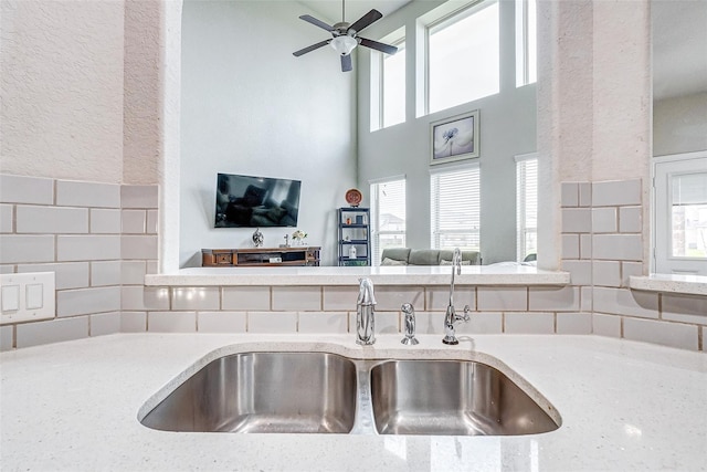 24030 Cannon Anello Ct, Katy, TX 77493 - kitchen featuring a towering ceiling, backsplash, a ceiling fan, light stone counters, and open floor plan