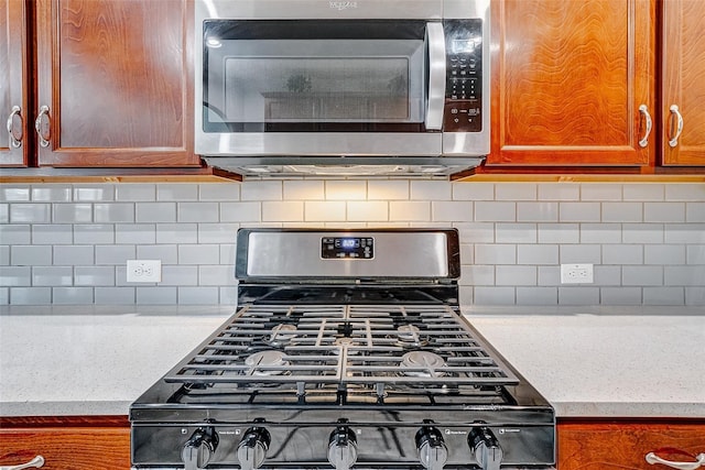 24030 Cannon Anello Ct, Katy, TX 77493 - detailed view of stainless steel microwave, range with gas stovetop, decorative backsplash, and brown cabinetry