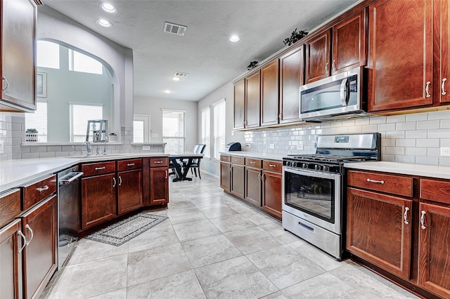 24030 Cannon Anello Ct, Katy, TX 77493 - kitchen featuring appliances with stainless steel finishes, backsplash, light countertops, recessed lighting, and arched walkways