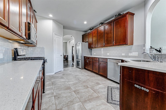 24030 Cannon Anello Ct, Katy, TX 77493 - kitchen featuring stainless steel appliances, arched walkways, light stone countertops, tasteful backsplash, and recessed lighting