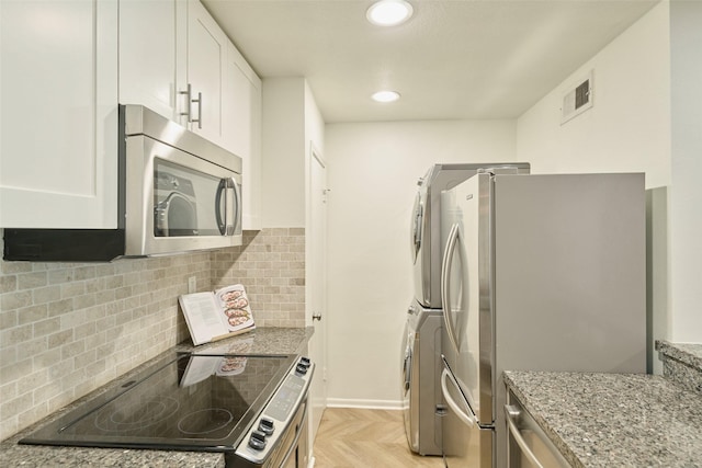 1601 S Shepherd Dr Unit 222, Houston, TX 77019 - kitchen featuring stainless steel appliances, light stone countertops, white cabinetry, backsplash, and stacked washer / dryer