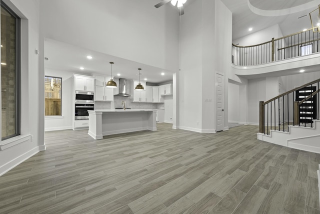 3232 Stingray Cove Dr, Katy, TX 77493 - unfurnished living room featuring a high ceiling, light wood-style floors, stairway, a ceiling fan, and recessed lighting