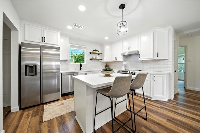 1610 Antoine Dr, Houston, TX 77055 - kitchen featuring appliances with stainless steel finishes, under cabinet range hood, white cabinetry, decorative backsplash, and recessed lighting