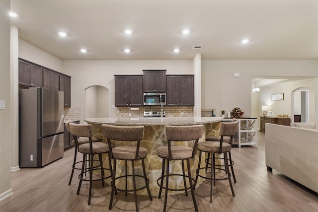 26410 Yaupon Crk, Magnolia, TX 77355 - kitchen with appliances with stainless steel finishes, arched walkways, dark brown cabinetry, and recessed lighting