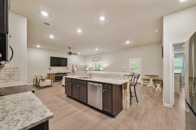 26410 Yaupon Crk, Magnolia, TX 77355 - kitchen featuring appliances with stainless steel finishes, open floor plan, dark brown cabinets, light wood-style floors, and a ceiling fan