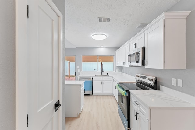 9323 Goodmeadow Dr, Houston, TX 77064 - kitchen featuring stainless steel appliances, light wood-style floors, a textured ceiling, white cabinets, and light stone counters