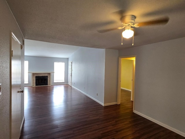 7400 Bellerive Dr Unit 1504, Houston, TX 77036 - unfurnished living room featuring ceiling fan, dark wood-style flooring, a fireplace with flush hearth, and a textured ceiling