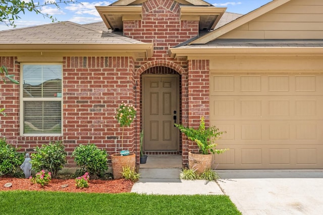 1055 Rancho Grande Dr, Channelview, TX 77530 - doorway to property featuring brick siding, an attached garage, driveway, and roof with shingles