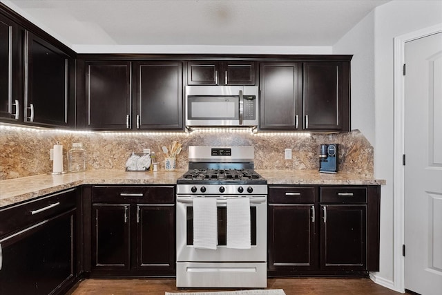 1055 Rancho Grande Dr, Channelview, TX 77530 - kitchen with stainless steel appliances, dark wood-style floors, decorative backsplash, and light stone countertops