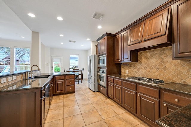 2513 Garnetfield Ln, Friendswood, TX 77546 - kitchen with appliances with stainless steel finishes, backsplash, light tile patterned floors, dark stone counters, and recessed lighting