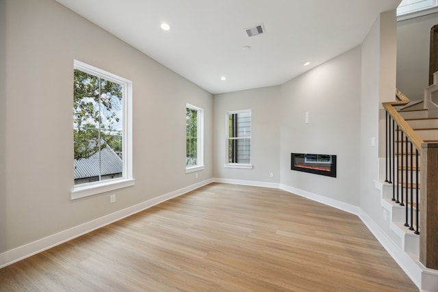 812 Thornton St Unit D, Houston, TX 77018 - unfurnished living room featuring stairs, light wood-style flooring, heating unit, recessed lighting, and a glass covered fireplace