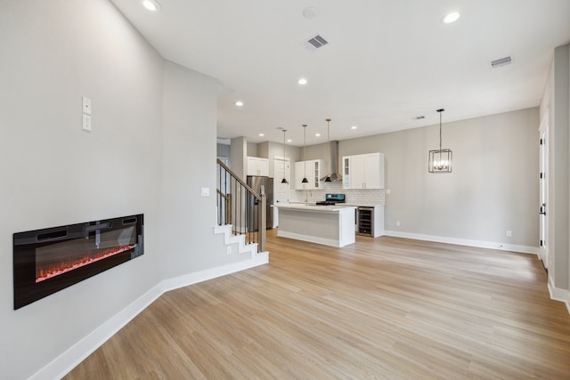 812 Thornton St Unit D, Houston, TX 77018 - unfurnished living room featuring a glass covered fireplace, light wood-type flooring, stairway, recessed lighting, and beverage cooler