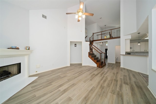 2111 Scenic Hollow Ct, Katy, TX 77450 - unfurnished living room featuring high vaulted ceiling, wood finished floors, ceiling fan, stairway, and a fireplace
