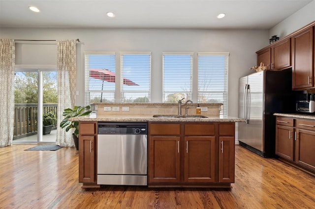 2841 Sherwin St, Houston, TX 77007 - kitchen featuring appliances with stainless steel finishes, wood finished floors, recessed lighting, a center island with sink, and light stone countertops