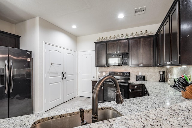 901 Jefferson Ave, Cleveland, TX 77327 - kitchen featuring black appliances, light stone countertops, dark brown cabinets, tasteful backsplash, and recessed lighting
