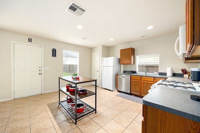 814 Eagles Glide Dr, Houston, TX 77090 - kitchen with white appliances, healthy amount of natural light, brown cabinetry, light tile patterned flooring, and recessed lighting
