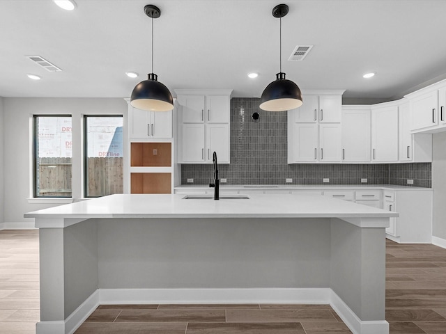3185 Stingray Cove Dr, Katy, TX 77493 - kitchen featuring light wood-style floors, backsplash, a spacious island, white cabinetry, and light countertops