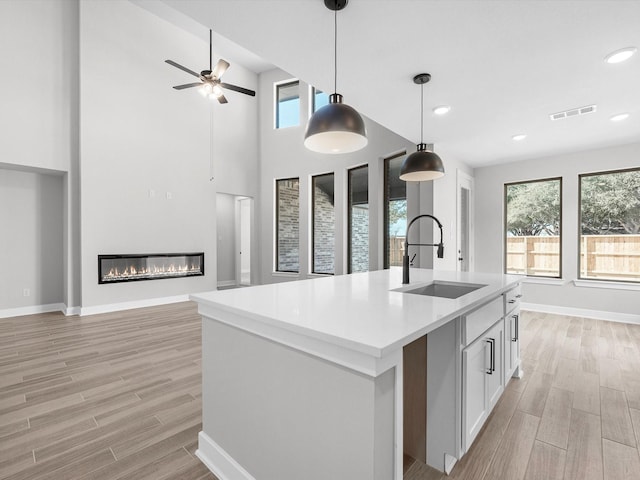 3185 Stingray Cove Dr, Katy, TX 77493 - kitchen featuring open floor plan, light wood finished floors, a glass covered fireplace, recessed lighting, and a towering ceiling