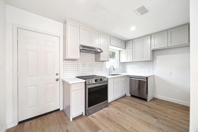 5859 Belmark St, Houston, TX 77033 - kitchen featuring appliances with stainless steel finishes, under cabinet range hood, tasteful backsplash, light wood finished floors, and recessed lighting