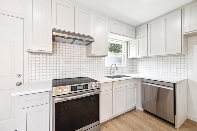 5859 Belmark St, Houston, TX 77033 - kitchen featuring stainless steel appliances, ventilation hood, light countertops, tasteful backsplash, and light wood-style floors