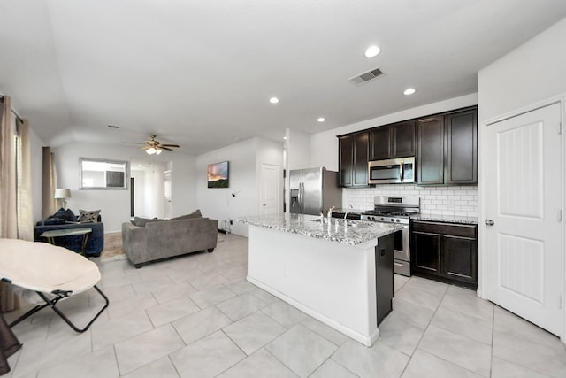 1404 Woods Lake Ct, Houston, TX 77047 - kitchen featuring appliances with stainless steel finishes, ceiling fan, backsplash, open floor plan, and light stone countertops