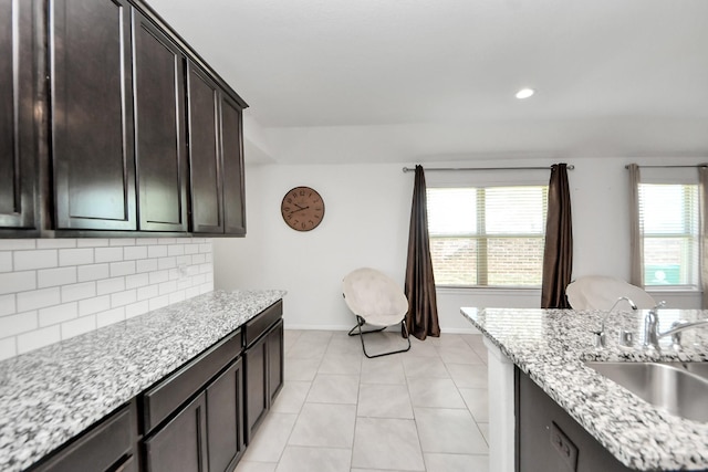 1404 Woods Lake Ct, Houston, TX 77047 - kitchen with tasteful backsplash, dark brown cabinetry, light stone countertops, recessed lighting, and light tile patterned floors
