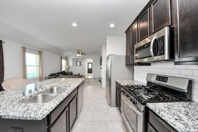 1404 Woods Lake Ct, Houston, TX 77047 - kitchen with appliances with stainless steel finishes, a center island with sink, decorative backsplash, ceiling fan, and healthy amount of natural light