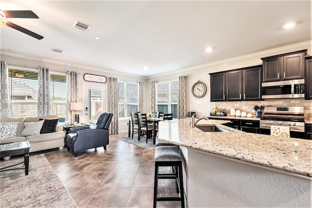 31144 Aspen Gate Trl, Spring, TX 77386 - kitchen featuring appliances with stainless steel finishes, ceiling fan, ornamental molding, open floor plan, and light stone countertops