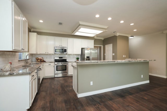 9111 Sutter Ranch Dr, Houston, TX 77064 - kitchen with appliances with stainless steel finishes, ornamental molding, a kitchen island, decorative backsplash, and white cabinetry
