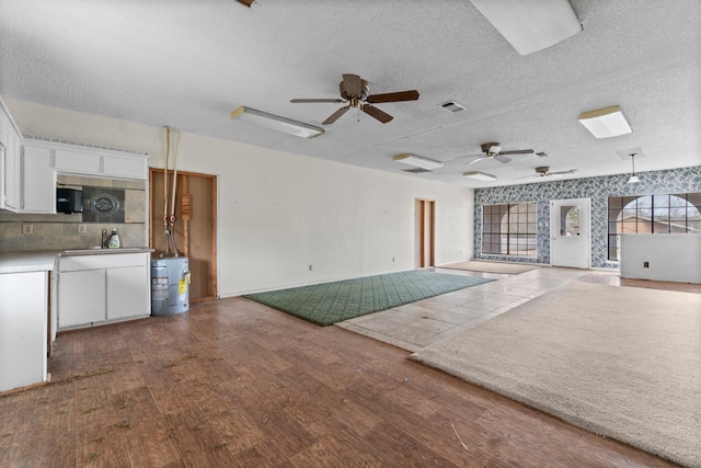 6738 US Highway 190 E, Livingston, TX 77351 - unfurnished living room with ceiling fan, wood finished floors, a textured ceiling, and electric water heater