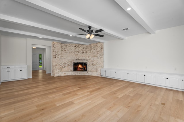 3 Briarwood Dr, Conroe, TX 77301 - unfurnished living room with light wood-style flooring, beamed ceiling, a ceiling fan, and a fireplace