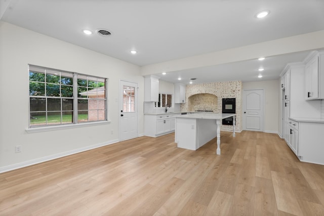 3 Briarwood Dr, Conroe, TX 77301 - kitchen with a breakfast bar area, a kitchen island, light countertops, light wood-type flooring, and decorative backsplash