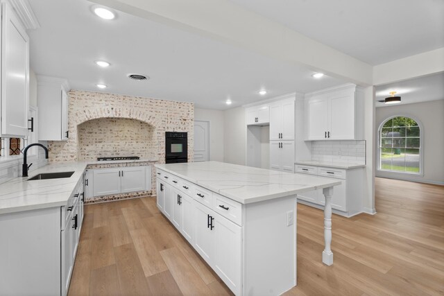 3 Briarwood Dr, Conroe, TX 77301 - kitchen featuring light wood-style floors, backsplash, recessed lighting, a kitchen island, and light stone counters