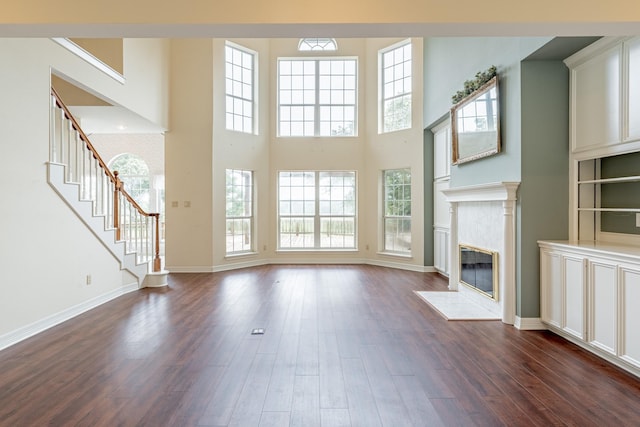 13141 Nicholson Rd, Conroe, TX 77303 - unfurnished living room featuring a high end fireplace, dark wood-type flooring, healthy amount of natural light, and a high ceiling