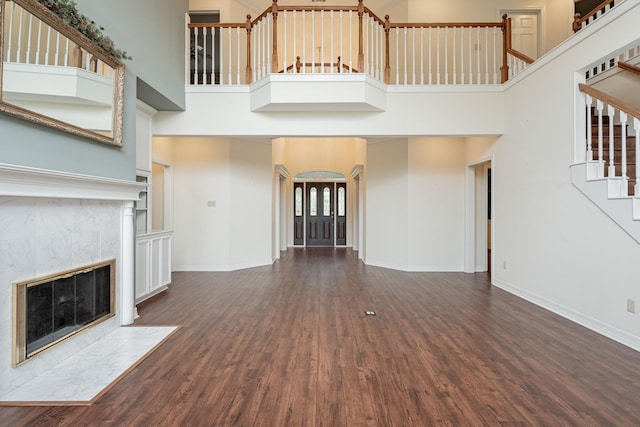 13141 Nicholson Rd, Conroe, TX 77303 - unfurnished living room with a towering ceiling, wood finished floors, stairs, arched walkways, and a tile fireplace
