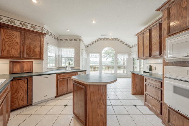 13141 Nicholson Rd, Conroe, TX 77303 - kitchen with white appliances, a center island, backsplash, wallpapered walls, and light tile patterned floors