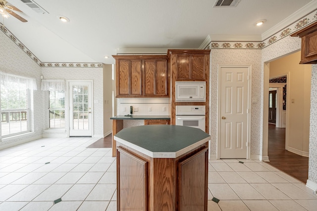 13141 Nicholson Rd, Conroe, TX 77303 - kitchen featuring white appliances, wallpapered walls, light tile patterned flooring, a center island, and crown molding