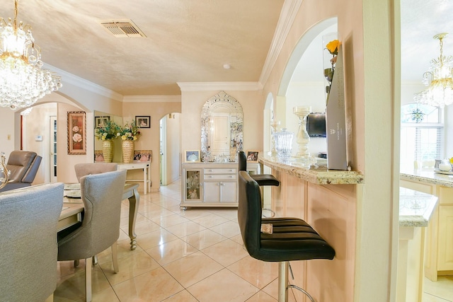 9411 Kingsvalley St, Houston, TX 77075 - kitchen featuring arched walkways, a chandelier, light tile patterned floors, ornamental molding, and a kitchen bar