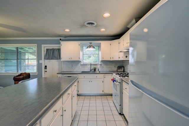 204 Meadow Ln, Brenham, TX 77833 - kitchen featuring freestanding refrigerator, white gas range, dark countertops, white cabinetry, and ornamental molding