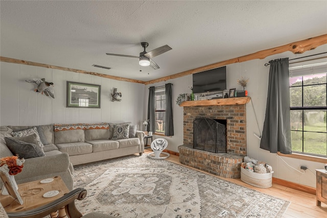 1205 W Houston Ave W, Crockett, TX 75835 - living area featuring a textured ceiling, wood finished floors, a fireplace, and ceiling fan
