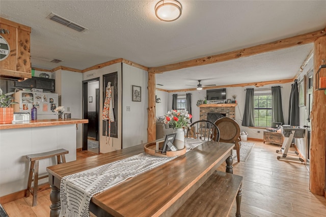1205 W Houston Ave W, Crockett, TX 75835 - dining area featuring light wood-style floors, ceiling fan, a brick fireplace, a textured ceiling, and crown molding
