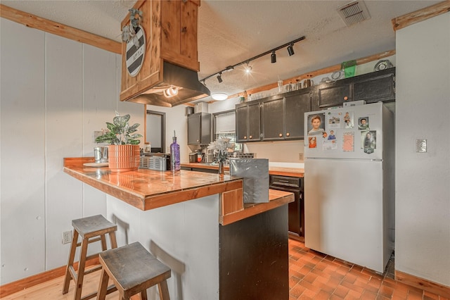 1205 W Houston Ave W, Crockett, TX 75835 - kitchen with freestanding refrigerator, a breakfast bar area, butcher block counters, a peninsula, and track lighting