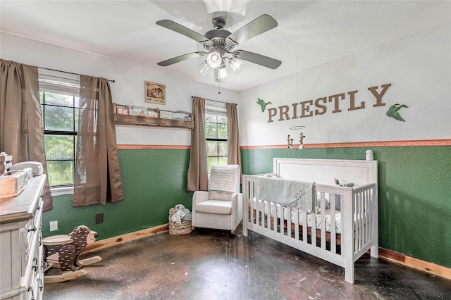 1205 W Houston Ave W, Crockett, TX 75835 - bedroom with multiple windows, a crib, a textured wall, finished concrete flooring, and ceiling fan
