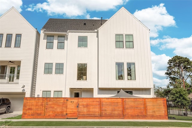 818 Fisher St, Houston, TX 77018 - view of side of property featuring board and batten siding, a fenced front yard, roof with shingles, and an attached garage